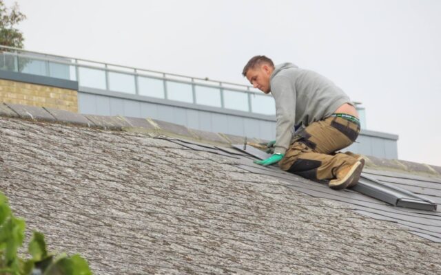Roofer working on an asphalt shingle roof repair
