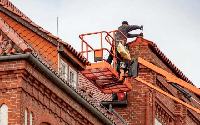 Roofer in a lift checking a residential roof